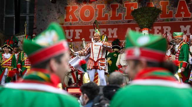 Beberapa orang menyaksikan pertunjukan saat menghadiri acara musim Karnaval di Cologne, Jerman barat, Kamis (24/2/2022). [Ina Fassbender / AFP]