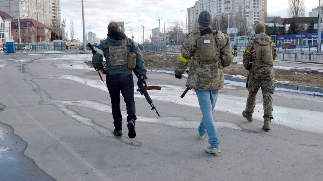 Pejuang Pertahanan Teritorial Ukraina berpatroli di jalan-jalan setelah pertempuran di Kharkiv, Ukraina, Minggu (27/2/2022). [Sergey BOBOK / AFP] 