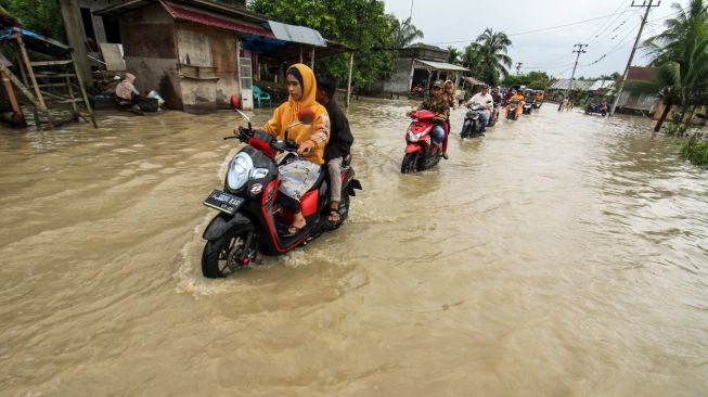 Warga berkendara sepeda motor menerobos banjir di Desa Meunasah Joek, Lhoksukon, Aceh Utara, Aceh, Senin (28/2/2022).  [ANTARA FOTO/Rahmad/tom]