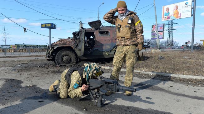 Pejuang Pertahanan Teritorial Ukraina menguji peluncur granat otomatis yang diambil dari kendaraan infanteri Rusia GAZ Tigr yang hancur setelah pertempuran di Kharkiv, Ukraina, Minggu (27/2/2022). [Sergey BOBOK / AFP] 