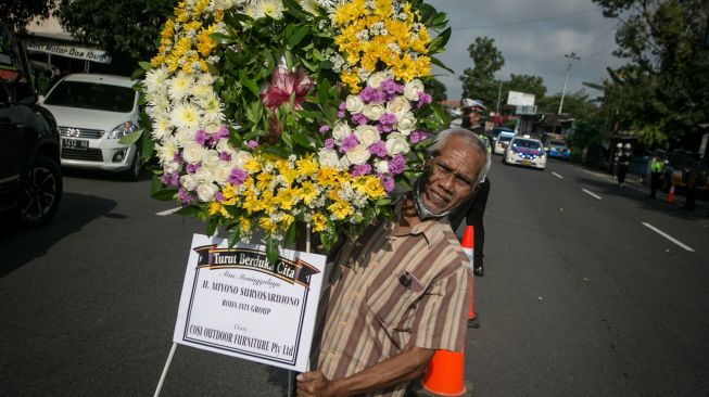 Warga membawa karangan bunga ucapan duka cita meninggalnya almarhum Miyono Suryasardjono ke rumah duka di Kampung Gondang, Banjarsari, Solo, Jawa Tengah, Senin (28/2/2022). [ANTARA FOTO/Mohammad Ayudha/hp]