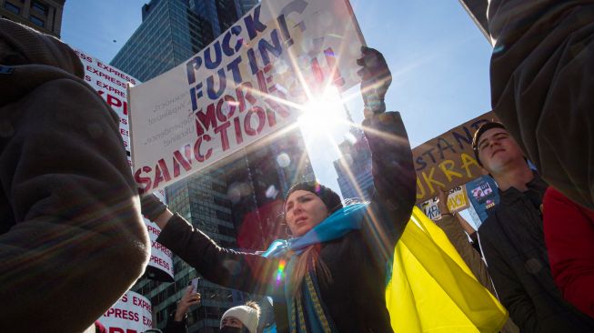 Seorang demonstran membawa poster saat protes mendukung Ukraina di Times Square, New York, Amerika, Sabtu (26/2/2022). [Kena Betancur / AFP]