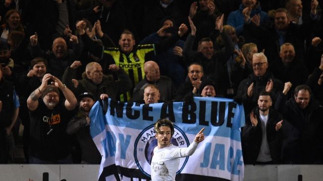 Gelandang serang Manchester City, Jack Grealish merayakan golnya ke gawang Peterborough United pada laga Piala FA di Weston Homes Stadium, Peterborough, Inggris, Rabu (2/3/2022) dini hari WIB. [Oli SCARFF / AFP]