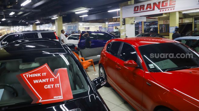 Pengunjung melihat mobil di bursa mobil bekas, blok M, Jakarta Selatan, Jumat (4/3/2022). [Suara.com/Alfian Winanto]