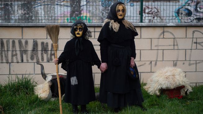 Dua orang berdandan dan mengenakan kostum penyihir saat karnaval tradisional Alsasua di Alsasua, provinsi Navarra, Spanyol, Selasa, (1/3/2022). [ANDER GILLENEA / AFP]