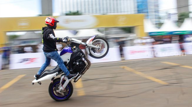 Pengendara melakukan atraksi motor saat Pameran UMKM Goes To Mandalika di Gedung Smesco, Jakarta Selatan, Minggu (6/3/2022). [Suara.com/Septian]