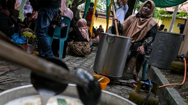 Seorang wanita menyiapkan saus untuk serabi (apam) makanan tradisional Indonesia saat Festival Kuliner Tradisional Tet Apam (memasak serabi) di Anjungan Pekan Kebudayaan Aceh (PKA) Taman Ratu Safiatuddin, Banda Aceh, Aceh, Sabtu (5/3/2022). [CHAIDEER MAHYUDDIN / AFP]
