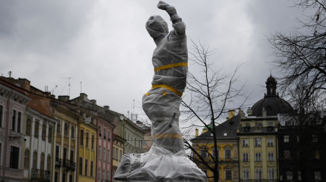 Sebuah patung bersejarah dibungkus di dekat gedung dewan kota di Lviv, Ukraina, Sabtu (5/3/2022). [Daniel LEAL / AFP]