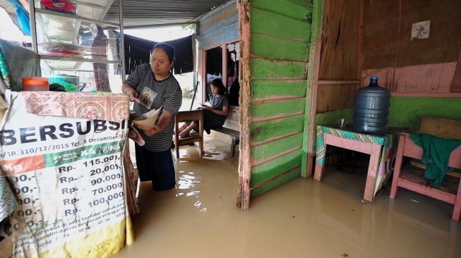 Pemilik warung makan melayani pembeli di depan rumahnya yang tergenang banjir di Kota Baru, Jambi, Minggu (6/3/2022). [ANTARA FOTO/Wahdi Septiawan/foc]