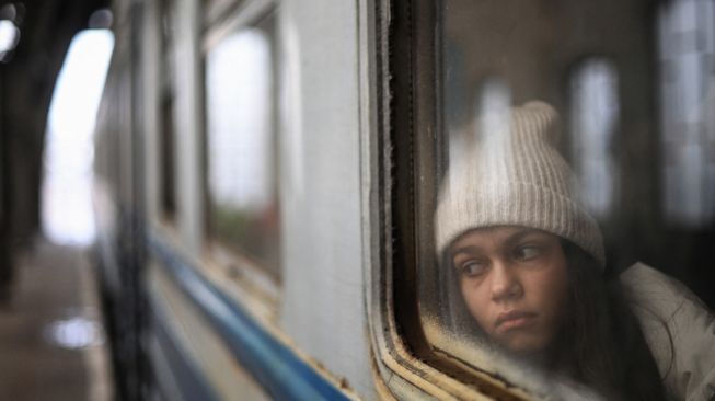 Seorang gadis melihat keluar dari jendela saat dia menunggu di dalam kereta yang membawa pengungsi ke Polandia di stasiun kereta Lviv, Ukraina barat, Sabtu (5/3/2022). [Daniel LEAL / AFP]