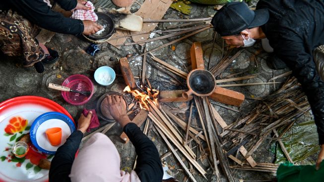 SeOrang - orang memasak (apam) makanan tradisional Indonesia saat Festival Kuliner Tradisional Tet Apam (memasak serabi) di Anjungan Pekan Kebudayaan Aceh (PKA) Taman Ratu Safiatuddin, Banda Aceh, Aceh, Sabtu (5/3/2022). [CHAIDEER MAHYUDDIN / AFP]