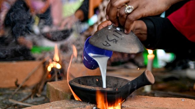 Orang - orang memasak serabi (apam) makanan tradisional Indonesia ssaat Festival Kuliner Tradisional Tet Apam (memasak serabi) di Anjungan Pekan Kebudayaan Aceh (PKA) Taman Ratu Safiatuddin, Banda Aceh, Aceh, Sabtu (5/3/2022). [CHAIDEER MAHYUDDIN / AFP]
