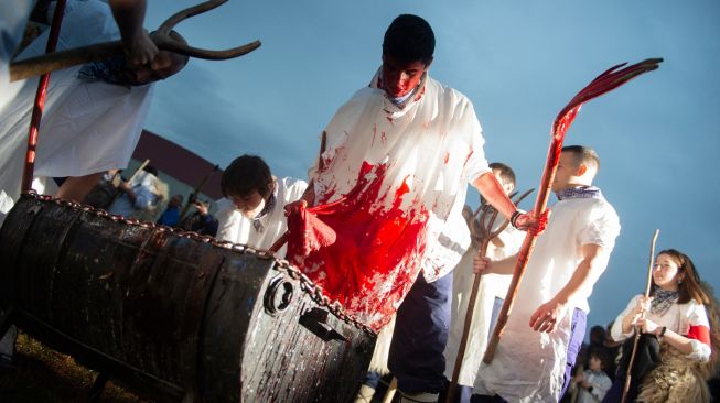 Orang-orang mengolesi wajah, lengan, dan kostum Momotxorro mereka dengan darah sapi saat karnaval tradisional Alsasua di Alsasua, provinsi Navarra, Spanyol, Selasa, (1/3/2022). [ANDER GILLENEA / AFP]