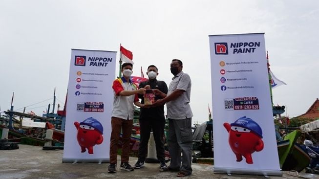 Topan Wijaksono, Area Sales Manager Jawa Tengah Nippon Paint Indonesia menyerahkan cat kepada Adi Susanto, Sekretaris Desa dan Warkuto, Ketua Forum Nelayan.