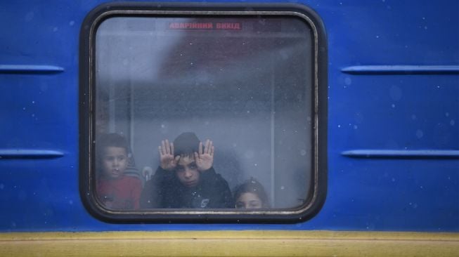 Anak-anak melihat melalui jendela kereta untuk mengungsi dari Ukraina di stasiun kereta api Lviv, Ukraina barat, Sabtu (5/3/2022). [Daniel LEAL / AFP]