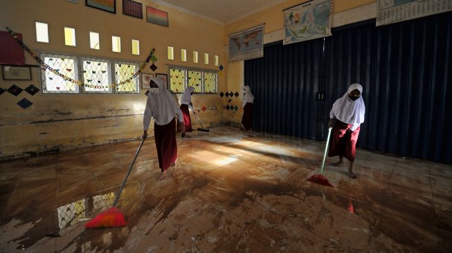 Pelajar membersihkan lantai kelas yang terdampak banjir di SDN 98 Kota Jambi, Kota Baru, Jambi, Senin (7/3/2022). [ANTARA FOTO/Wahdi Septiawan/rwa]