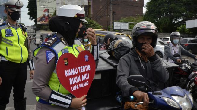 Anggota Satlantas Polda Lampung memberikan edukasi keselamatan berkendara dan prokes kepada pengendara saat pelaksanaan saat Operasi Keselamatan Krakatau 2022 di Bandar Lampung, Lampung, Senin (7/3/2022). [ANTARA FOTO/Ardiansyah/rwa]