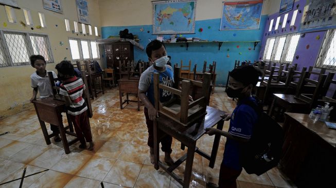 Pelajar memindahkan meja dan kursi kelas yang terdampak banjir di SDN 98 Kota Jambi, Kota Baru, Jambi, Senin (7/3/2022). [ANTARA FOTO/Wahdi Septiawan/rwa]