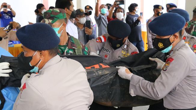 Petugas kepolisian dan TNI membawa kantong berisi jenazah teknisi tower telekomunikasi PT Palapa Timur Telematika (PTT) setibanya di RSUD Timika, Papua, Senin (7/3/2022). [ANTARA FOTO/Saldi Hermanto/wpa/rwa]