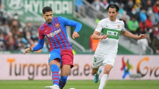 Pemain Barcelona Ronald Araujo melepaskan passing dalam pertandingan kontra Elche di pekan ke-28 La Liga, Minggu (6/3/2022). [AFP]