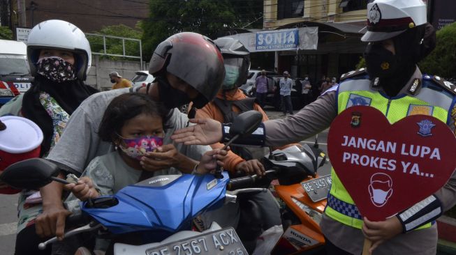 Anggota Satlantas Polda Lampung memberikan edukasi keselamatan berkendara dan prokes kepada pengendara saat pelaksanaan saat Operasi Keselamatan Krakatau 2022 di Bandar Lampung, Lampung, Senin (7/3/2022). [ANTARA FOTO/Ardiansyah/rwa]