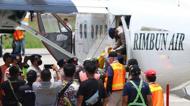 Petugas kepolisian dan TNI membawa kantong berisi jenazah teknisi tower telekomunikasi PT Palapa Timur Telematika (PTT) setibanya di Bandara Mozes Kilangin Timika, Papua, Senin (7/3/2022). [ANTARA FOTO/Saldi Hermanto/wpa/rwa]