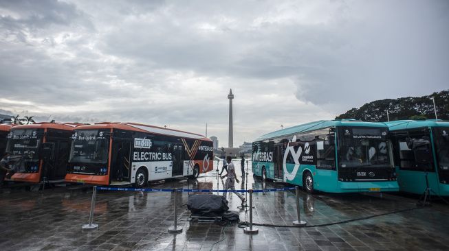 Petugas berjalan di dekat Bus Listrik Transjakarta di Plaza Monas, Jakarta, Selasa (8/3/2022). ANTARA FOTO/Aprillio Akbar
