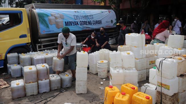 Petugas menata jerigen berisi minyak curah saat distribusi minyak goreng curah di Pasar Kebayoran Lama, Jakarta, Rabu (9/3/2022). [Suara.com/Angga Budhiyanto] 