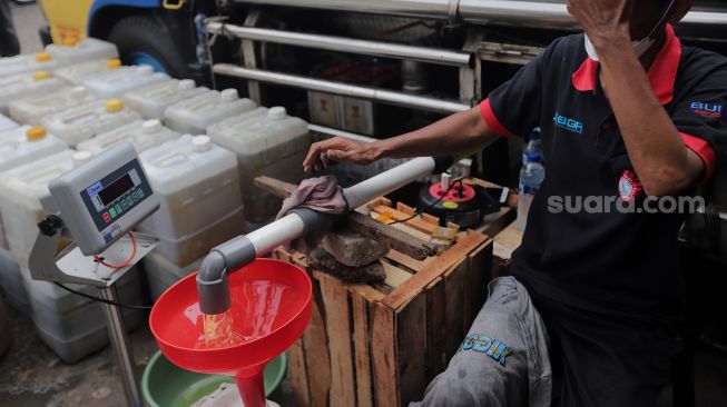 Petugas mengisi jerigen dengan minyak curah saat distribusi minyak goreng curah di Pasar Kebayoran Lama, Jakarta, Rabu (9/3/2022). [Suara.com/Angga Budhiyanto] 