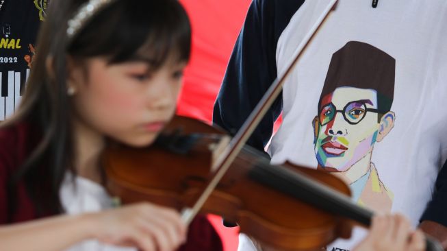 Seorang pelajar memainkan alat musik biola saat berziarah di makam WR Soepratman di Surabaya, Jawa Timur, Rabu (9/3/2022). ANTARA FOTO/Didik Suhartono