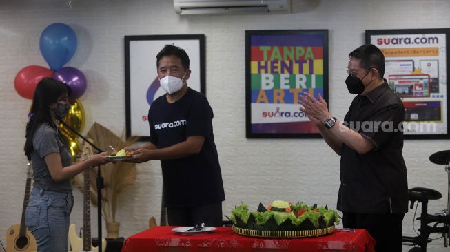 Pemimpin Redaksi portal-portal media PT Arkadia Digital Media Tbk, Suwarjono (tengah) memberikan potongan tumpeng kepada perwakilan SuaraJogja, disaksikan oleh Komisaris Utama PT Arkadia Digital Media Stephen K.Sulistyo (kanan) saat ulang tahun ke-8 Suara.com di Kantor Redaksi Suara.com, Mega Kuningan, Jakarta, Jumat (11/3/2022). [Suara.com/Angga Budhiyanto]