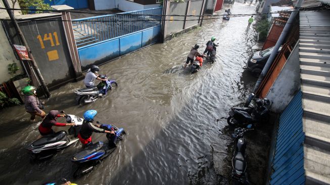 Pengendara motor melintas di jalan yang tergenang banjir di Desa Kureksari, Waru, Sidoarjo, Jawa Timur, Jumat (11/3/2022). . ANTARA FOTO/Umarul Faruq