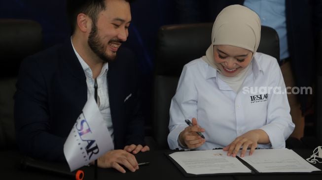 Pendiri Leslar Entertainment Lesti Kejora (kanan) didampingi Presiden Direktur Prestige Motorcars Rudy Salim menandatangani akuisisi Leslar Entertainment oleh Prestige Corp di Prestige Image Corp, Pluit, Jakarta, Jumat (11/3/2022). [Suara.com/Angga Budhiyanto]