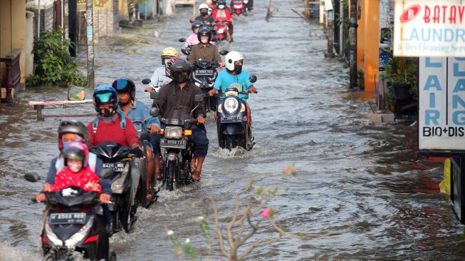 Pengendara motor melintas di jalan yang tergenang banjir di Desa Kureksari, Waru, Sidoarjo, Jawa Timur, Jumat (11/3/2022). ANTARA FOTO/Umarul Faruq