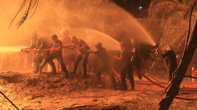 Sejumlah petugas pemadam kebakaran berusaha memadamkan api di sumur minyak ilegal yang berada di kawasan pemukiman penduduk Desa Mata Ie, Kecamatan Ranto Peureulak, Aceh Timur, Sabtu (12/3/2022).  ANTARA FOTO/Syifa Yulinnas
