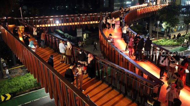 Sejumlah warga berfoto di Jembatan Penyeberangan Orang (JPO) Pinisi Karet-Sudirman, Jakarta, Sabtu (12/3/2022). [Suara.com/Angga Budhiyanto]