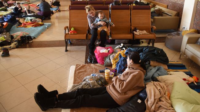 Wanita dan anak-anak mengungsi di stasiun kereta api kota Lviv, Ukraina, Jumat (11/3/2022). [Yuriy Diachyshyn / AFP]