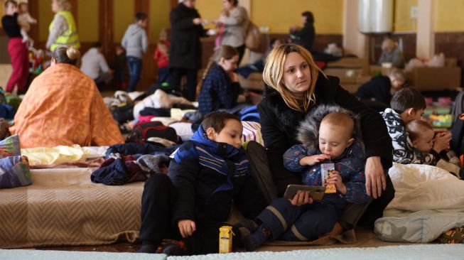 Wanita dan anak-anak mengungsi di stasiun kereta api kota Lviv, Ukraina, Jumat (11/3/2022). [Yuriy Diachyshyn / AFP]