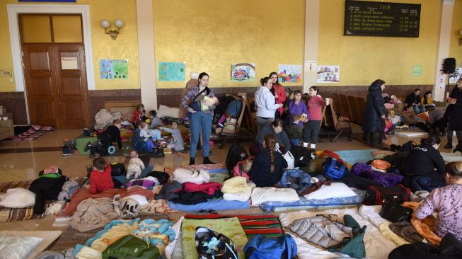 Wanita dan anak-anak mengungsi di stasiun kereta api kota Lviv, Ukraina, Jumat (11/3/2022). [Yuriy Diachyshyn / AFP]