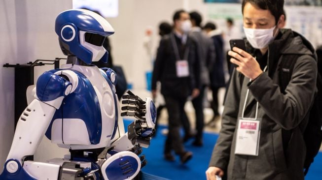 Seorang pengunjung mengambil gambar "HRP4", robot yang dikembangkan oleh Kawada Robotic di Pameran Robot Internasional di Tokyo, Jepang, Kamis (10/3/2022). [Philip FONG/AFP]