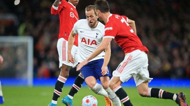 Striker Tottenham Hotspur Harry Kane (tengah) menggiring bola diantara striker Manchester United Marcus Rashford (kiri) dan gelandang Manchester United Nemanja Matic (kanan) saat pertandingan sepak bola Liga Premier Inggris antara Manchester United dan Tottenham Hotspur di Stadion Old Trafford, Manchester, Inggris, Sabtu (12/3/2022). [Lindsey Parnaby / AFP]