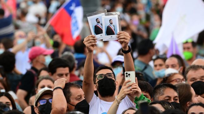 Pendukung Presiden baru Chili Gabriel Boric, menunggu di luar Istana La Moneda untuk pidato pertamanya di Santiago, Chili, Jumat (11/3/2022). [MARTIN BERNETTI / AFP]