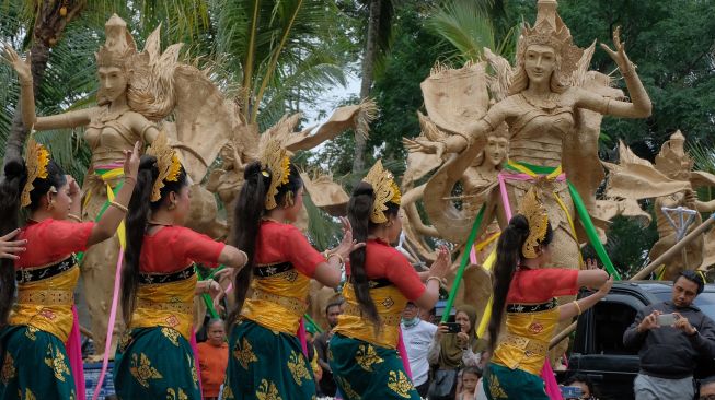 Sejumlah seniman menari di dekat patung sembilan bidadari berbahan anyaman bambu yang dipajang saat rangkaian pawai di Alas Harum Bali, Desa Tegallalang, Gianyar, Bali, Minggu (13/3/2022). [ANTARA FOTO/Nyoman Hendra Wibowo/hp]