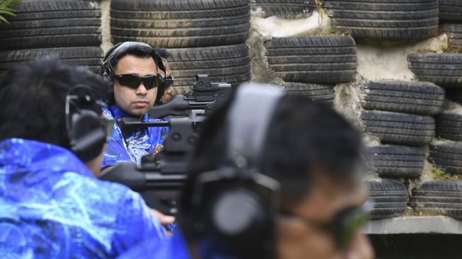 Selebritas Raffi Ahmad (kiri) bersiap mengikuti Lomba Menembak Piala Komandan Pasukan Pengamanan Presiden (Danpaspampres) 2022 dalam kelas ekshibisi 'Dueling Plate' di Lapangan Tembak Senayan, Jakarta, Minggu (13/3/2022). [ANTARA FOTO/M Risyal Hidayat/foc]