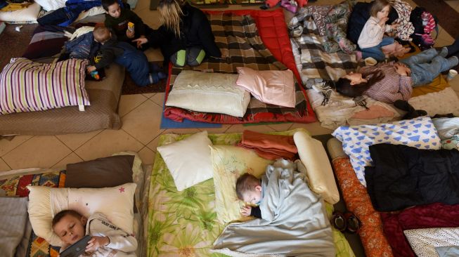 Wanita dan anak-anak mengungsi di stasiun kereta api kota Lviv, Ukraina, Jumat (11/3/2022). [Yuriy Diachyshyn / AFP]