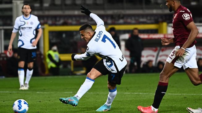 Penyerang Inter Milan Alexis Sanchez melakukan tendangan untuk menyamakan kedudukan saat pertandingan sepak bola Serie A Liga Italia antara Torino dan Inter Milan di stadion Olimpiade, Turin, Italia, Sabtu (13/3/2022). [Marco BERTORELLO / AFP]