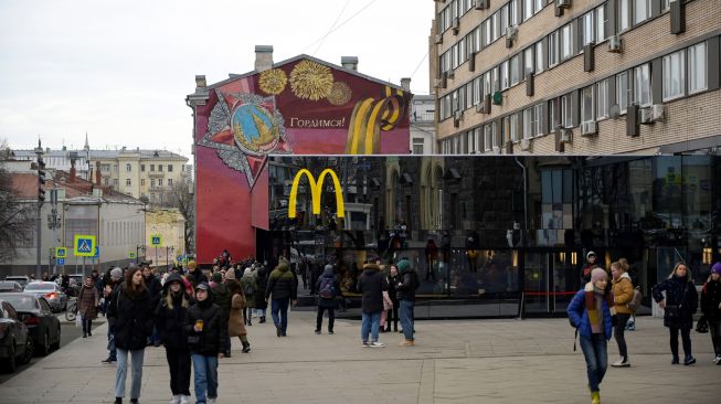 Orang-orang melintas di depan restoran McDonald's di Pushkinskaya Square di pusat kota Moskow, Rusia, Minggu (13/3/2022). [AFP]
