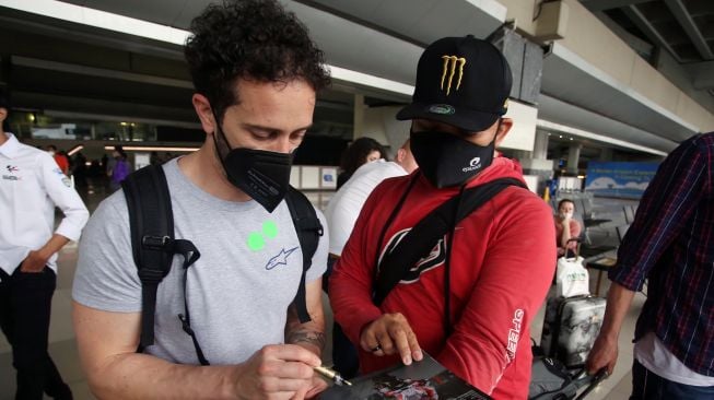 Pebalap MotoGP dari tim WithU Yamaha RNF Andrea Dovizioso membubuhkan tanda tangan untuk pengemar setibanya di Bandara Soekarno Hatta,Tangerang, Banten, Selasa (15/3/2022).  ANTARA FOTO/Muhammad Iqbal
