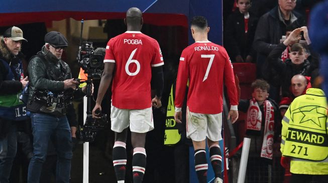 Gelandang Manchester United Paul Pogba (kiri) dan striker Manchester United Cristiano Ronaldo (kanan) langsung pergi setelah peluit akhir dibunyikan dalam pertandingan leg kedua babak 16 besar Liga Champions UEFA antara Manchester United melawan Atletico Madrid di Old Trafford, Rabu (16/3/2022) dini hari WIB. Paul ELLIS / AFP