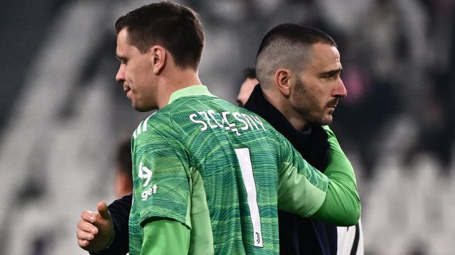 Bek Juventus Leonardo Bonucci (kanan) menghibur kiper Juventus Wojciech Szczesny pada akhir pertandingan leg kedua babak 16 besar UEFA Liga Champions antara Juventus dan Villarreal di Stadion Juventus, Turin, Italia, Rabu (17/3/2022). [Marco BERTORELLO / AFP]